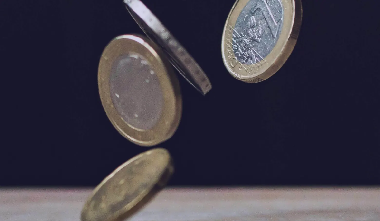 Fallende Euromünzen vor dunklem Hintergrund