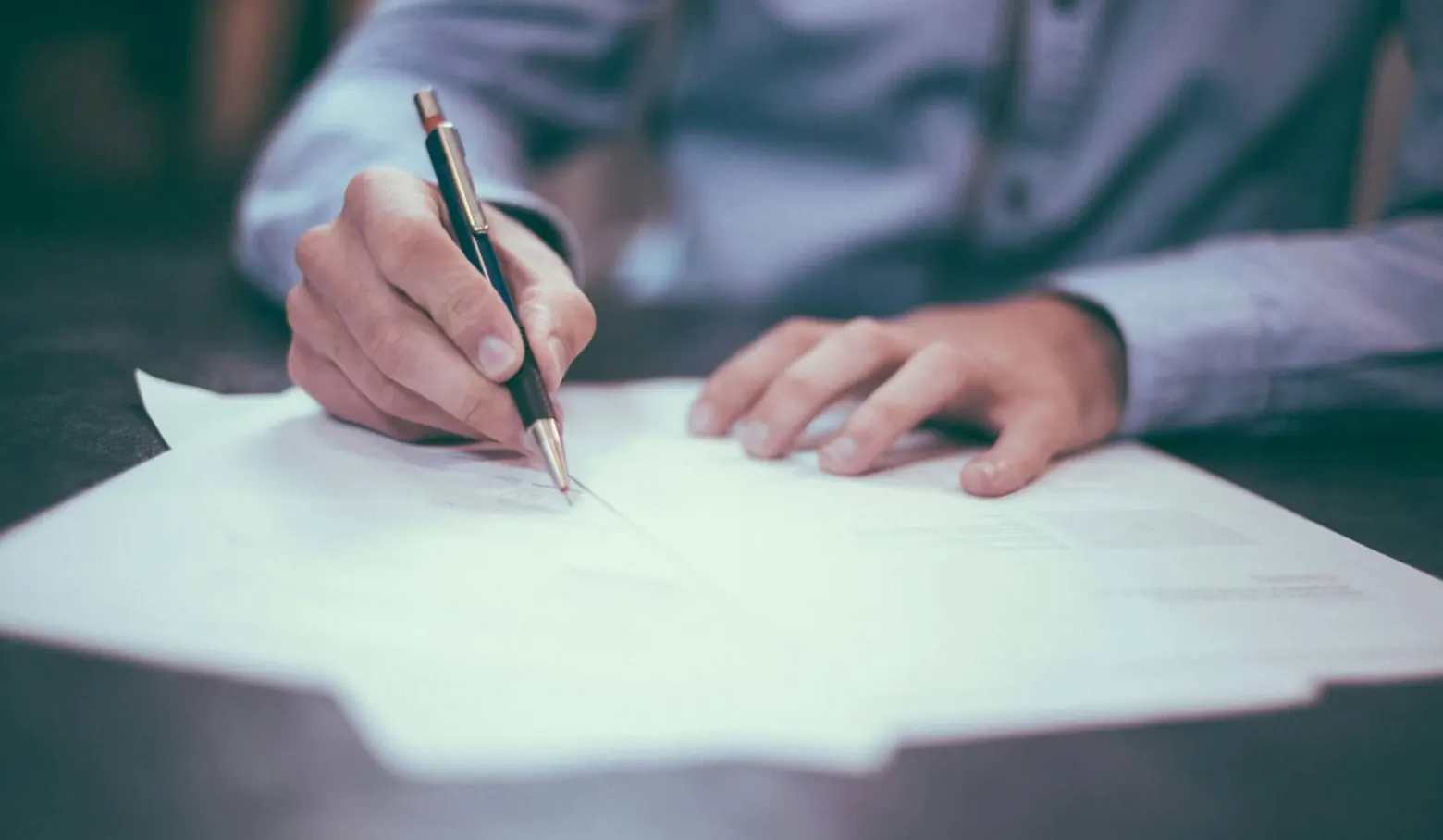 Hand schreibt mit einem Stift auf einem Blatt Papier