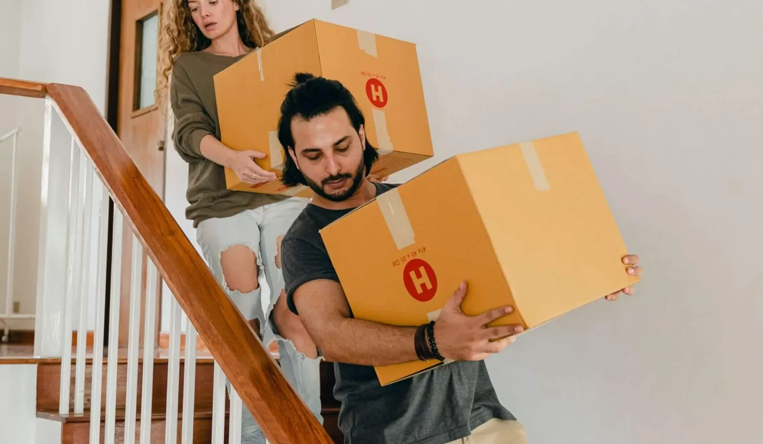 Zwei Personen tragen Umzugskartons eine Treppe hinunter