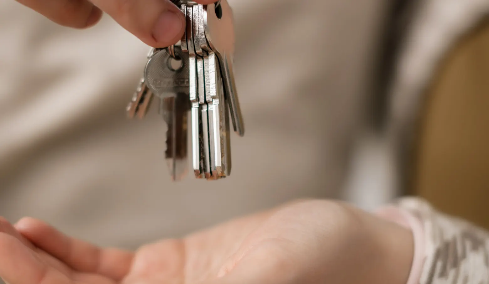 Schlüsselbund wird in eine geöffnete Hand übergeben